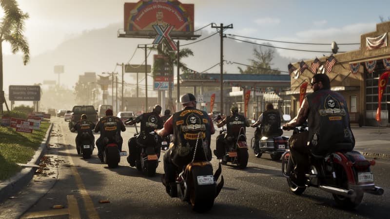 A biker club in skull-patched vests rides down a small-town main street past a gas station and a sheriff's office sign.