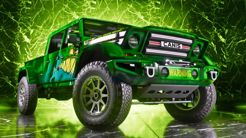 A green four-door Canis pickup with roof lights and airbrushed fish artwork on a polished showroom floor.