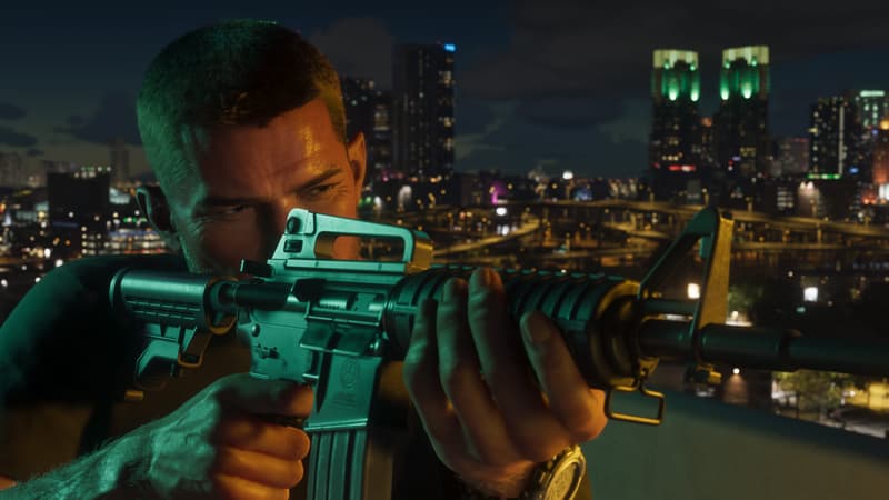 A man shoulders a short M4-style carbine on a rooftop at night, lit office towers glowing behind him.