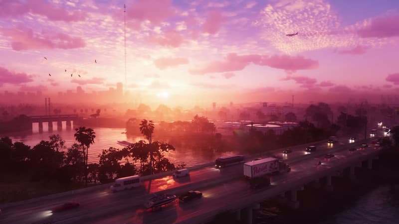Sunrise over a coastal freeway, traffic streaming past a lagoon toward distant towers