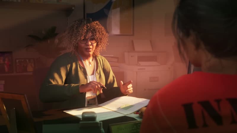 Corrections counsellor in glasses and a green cardigan across a desk from Lucia