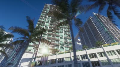 Glass condo towers and palm fronds seen looking straight up from a beachfront street