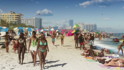 Beachgoers walking the sand past umbrellas, pastel hotels lining the shore behind