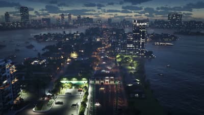Night aerial of a lit causeway and high-rises strung across dark bay water