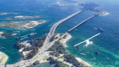 A seaplane banks over a causeway threading between shallow reef islands