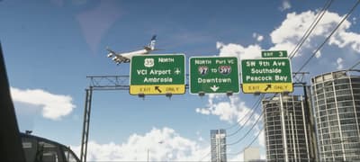 Freeway signs for VCI Airport, Downtown and Peacock Bay with a jet passing overhead