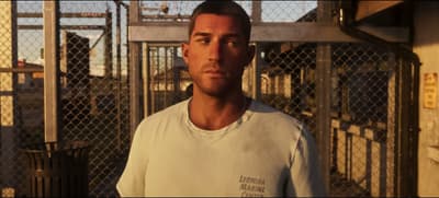 Jason waiting at the prison gate in a stained Leonida Marine Center T-shirt