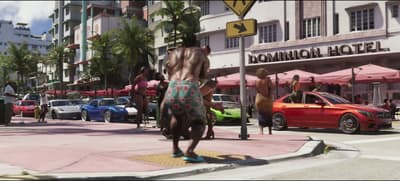 Dancers on an Ocean Drive corner beside parked supercars and cafe umbrellas