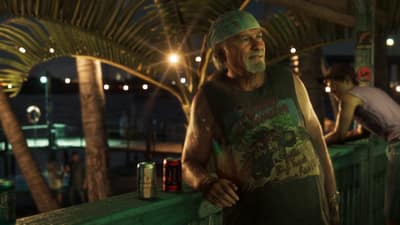 A grey-bearded man in a bandana leans on a dock rail beside beer cans, marina lights behind.