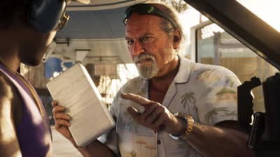 An older man in a palm-print shirt gestures at a taped brick of white powder aboard a plane.