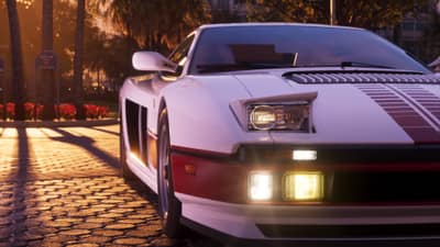 Front corner of a white and red wedge-shaped sports car on cobbles, foglights lit at sunset.