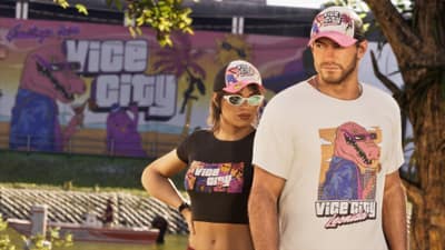 A couple in matching Vice City caps and cartoon alligator tees stand before a painted mural.
