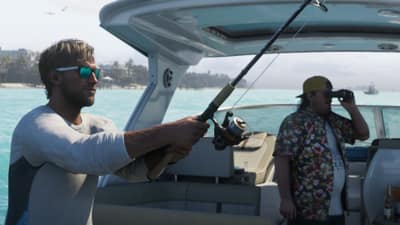 A man in mirrored sunglasses casts a fishing rod from a boat while another scans with binoculars.