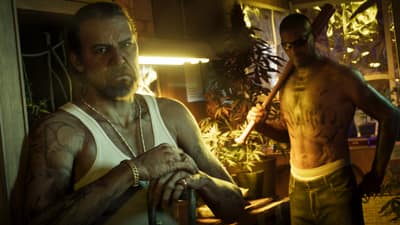 A tattooed man sits among cannabis plants under grow lights while another stands holding a bat.