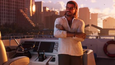 A man in a linen shirt stands arms folded at a yacht helm, city skyline behind at sunset.