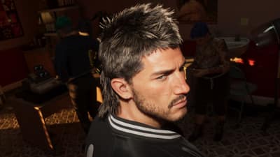 Profile of a man with a freshly cut spiked mullet as stylists work behind him.