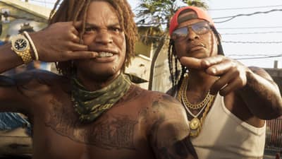 Two shirtless men pose for the camera in a sunlit yard, showing a gold grill and chains.