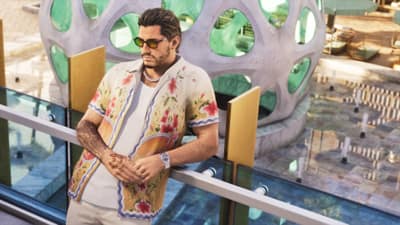 A man in a floral shirt and gold sunglasses leans on a glass rail above a pool deck.