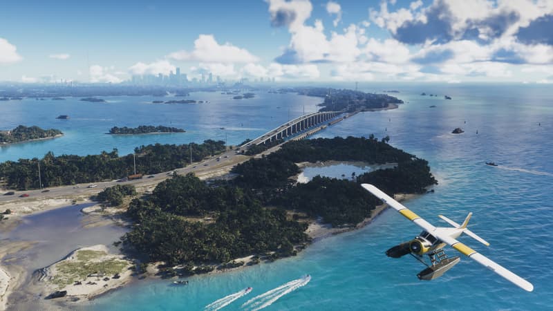 A seaplane banks over turquoise shallows and a long causeway bridge, with distant city towers on the horizon.