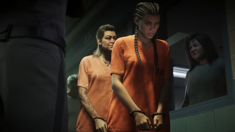Handcuffed women in orange jumpsuits file past a uniformed guard in a prison corridor.
