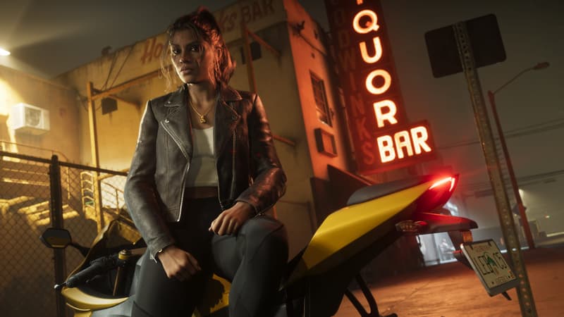 A woman in a leather jacket sits astride a yellow sportbike outside a bar's red neon liquor sign at night.