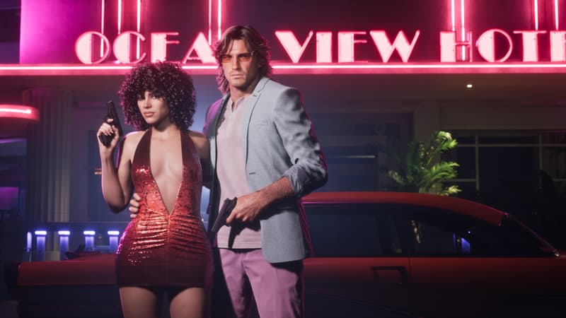 A man and woman in eighties clothes hold pistols on the sidewalk beneath the Ocean View Hotel's pink neon sign.