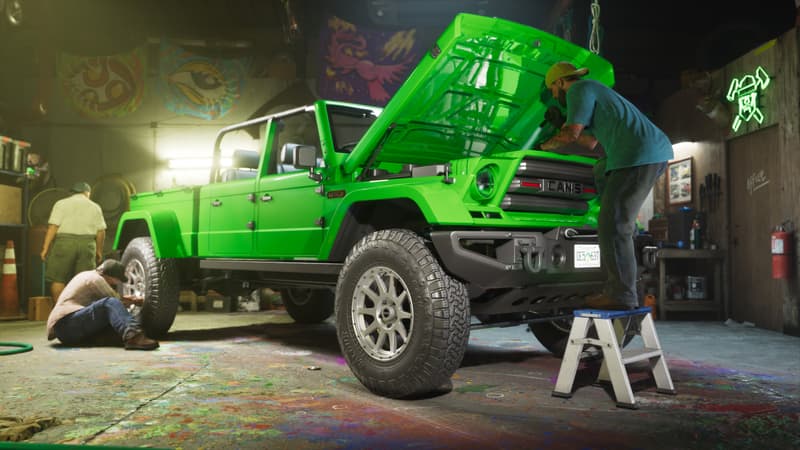 A bright green pickup sits on jack stands in a paint-spattered workshop while mechanics work around it.