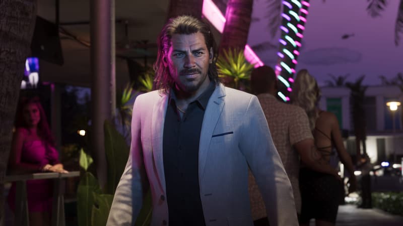 An older man in a pale linen blazer walks a palm-lined sidewalk at night under pink and turquoise neon.