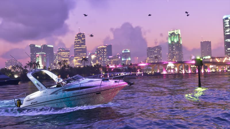 A pink and blue speedboat carves a wake across the bay at dusk with the city skyline behind.