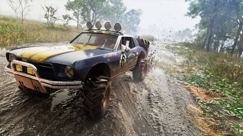 A mud-caked blue and yellow muscle car on oversized off-road tyres throws spray through a swamp.