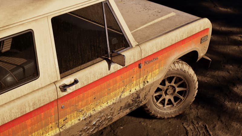 A mud-flecked white and orange off-road truck badged Riata, roof lights mounted above the windscreen.