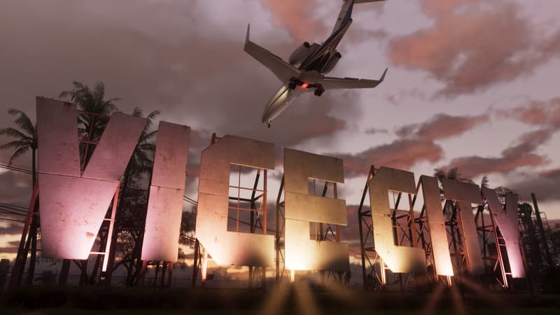 Giant weathered concrete letters spelling VICE CITY stand against a pink sunset as an airliner passes low overhead.